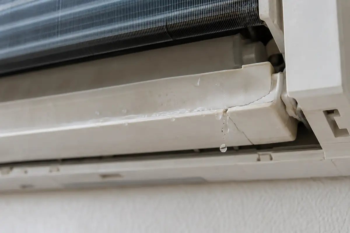 Water escaping through a fine crack in a residential AC condensate drain pan