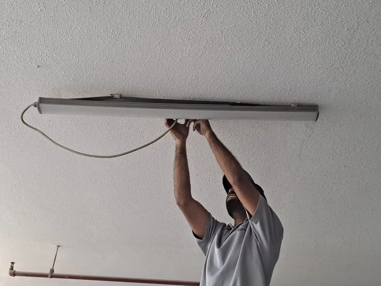 Technician installing an overhead light fitting in a Dubai parking area — supporting project view 1