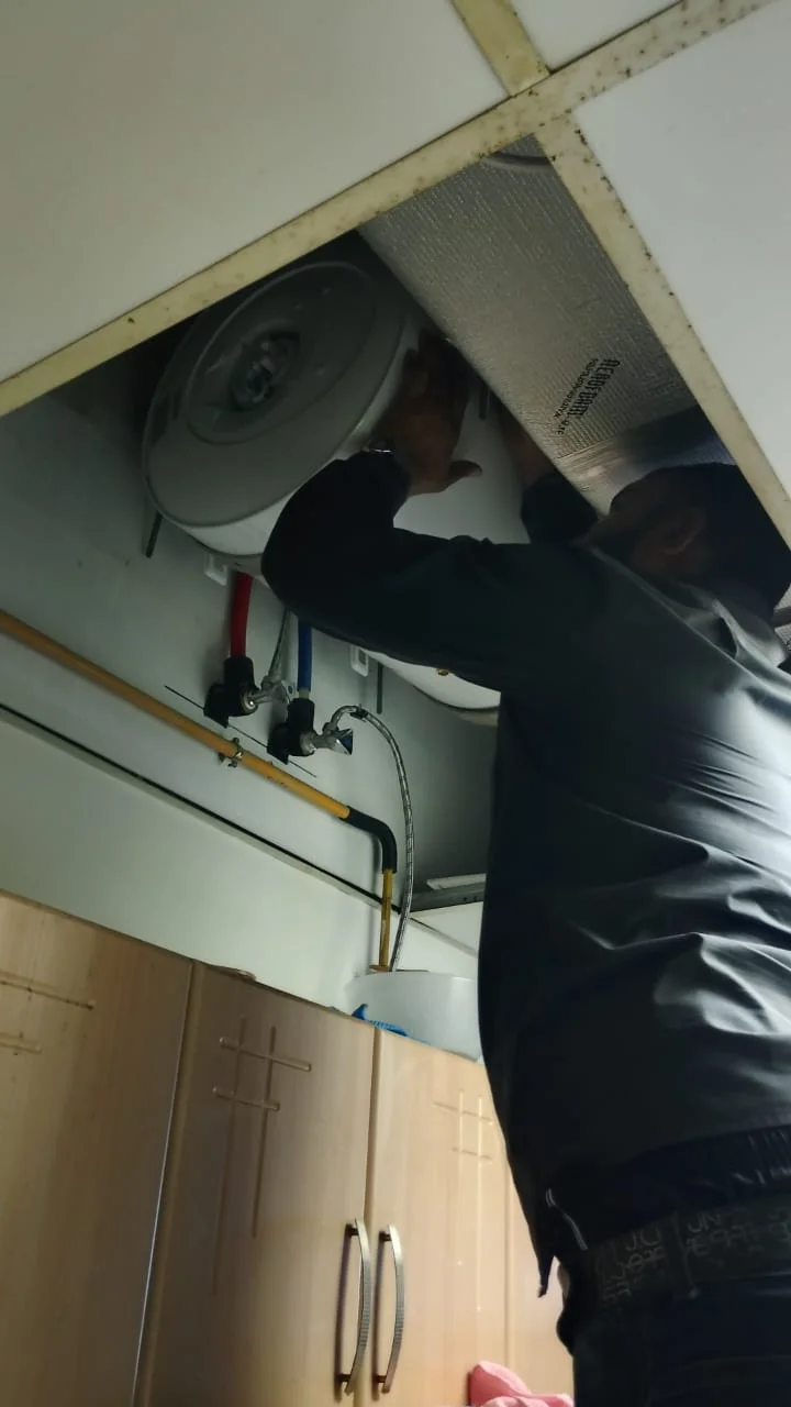 Technician repairing a water heater above a ceiling access panel in Dubai — supporting project view 2