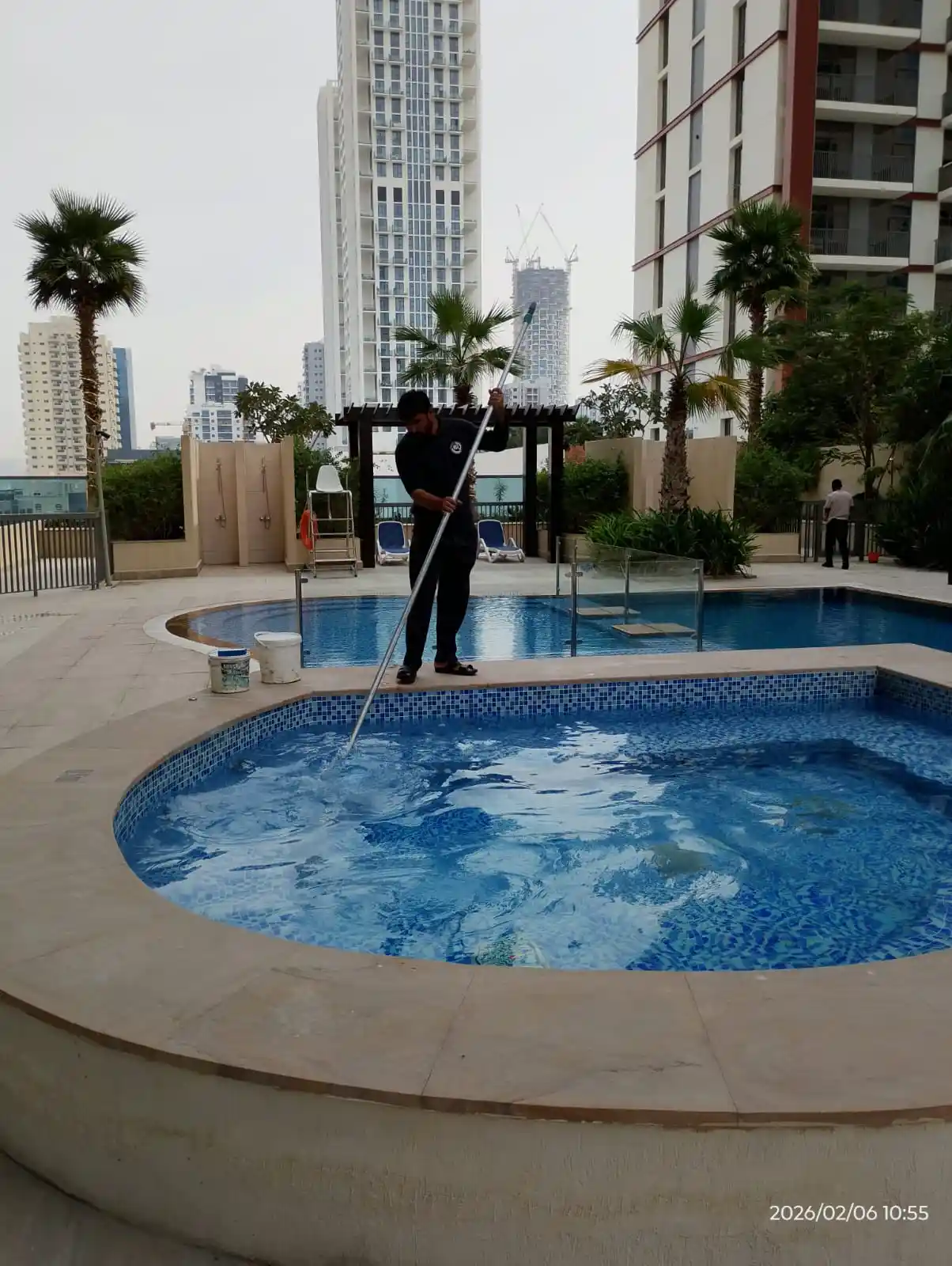 Technician cleaning an outdoor swimming pool in Dubai